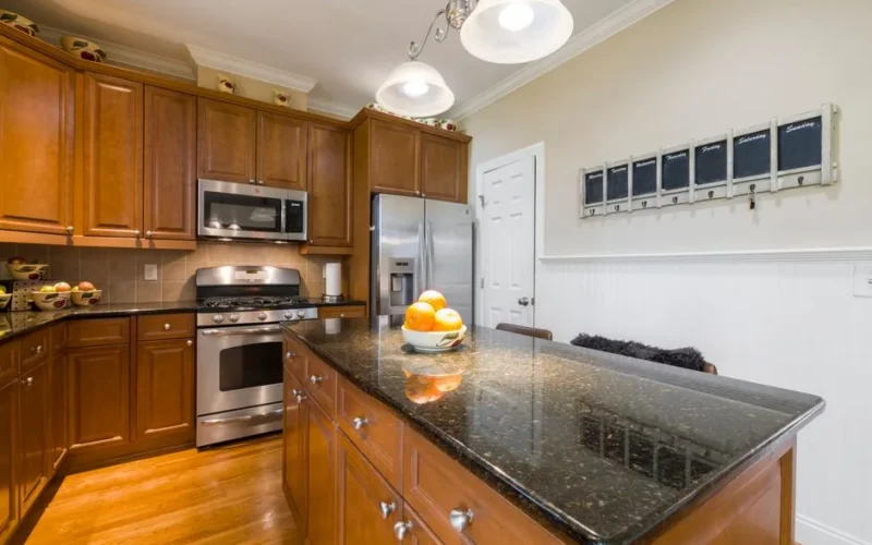 Bright kitchen featuring granite countertops, wooden cabinets, and stainless steel appliances.