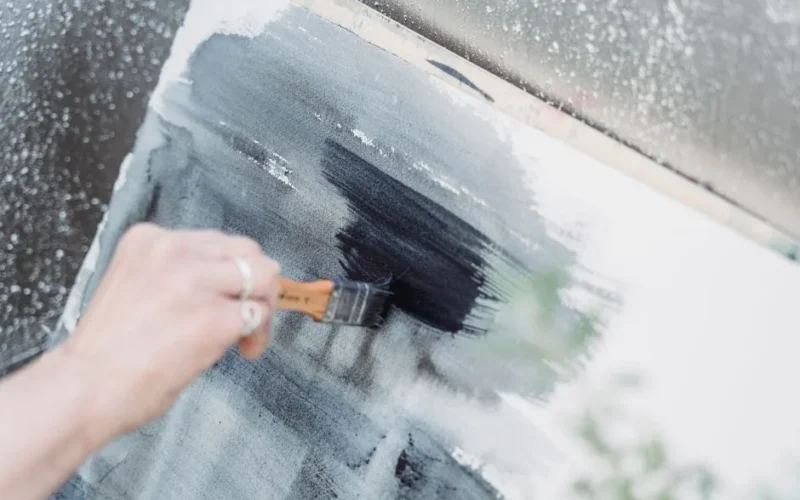 A close-up view of an artist painting with brush strokes on a canvas, showcasing creativity.