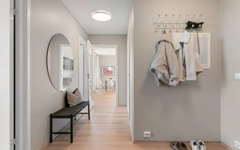A contemporary hallway with minimalist decor featuring coats, shoes, and a stylish mirror.