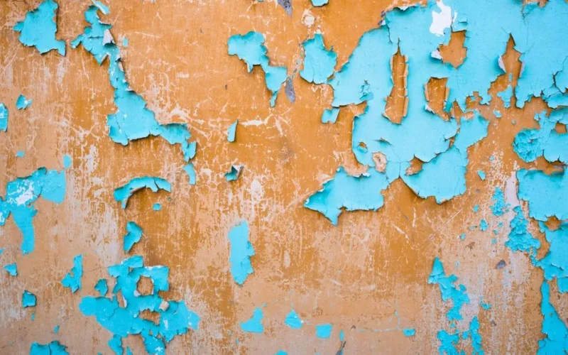 Vibrant wall featuring weathered blue and orange peeling paint with a textured surface.