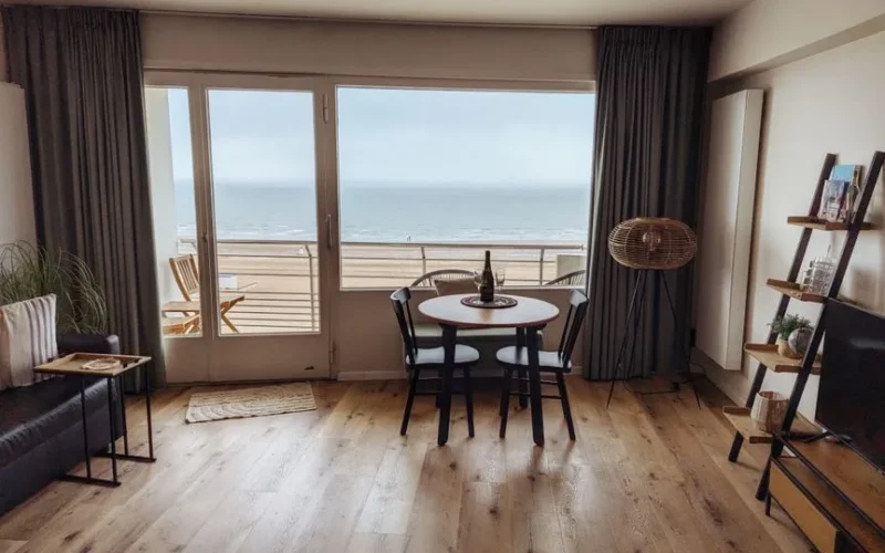 A cozy living room in a beachfront apartment with a stunning ocean view, featuring modern decor.