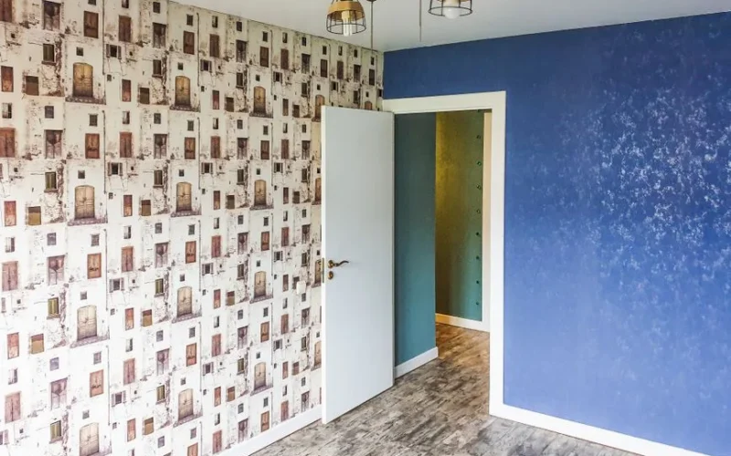 A modern room featuring a blue accent wall, unique patterned wallpaper, and contemporary lighting.