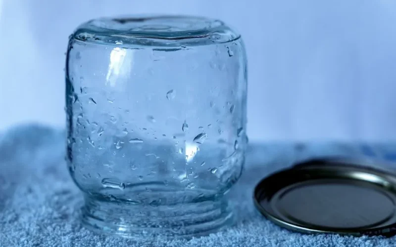 A transparent glass jar with a metal lid placed on a textured blue towel.