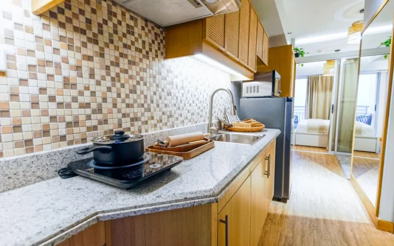 Spacious modern kitchen with induction cooktop, granite countertops, and wooden cabinets in a bright apartment.
