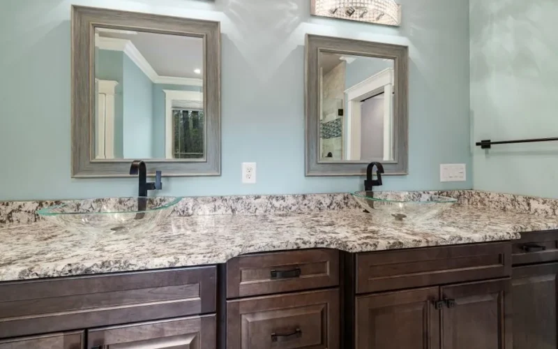 Stylish bathroom featuring dual glass bowl sinks and granite countertops.