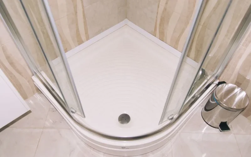 A clean, modern corner shower enclosure with glass doors in a tiled bathroom setting.