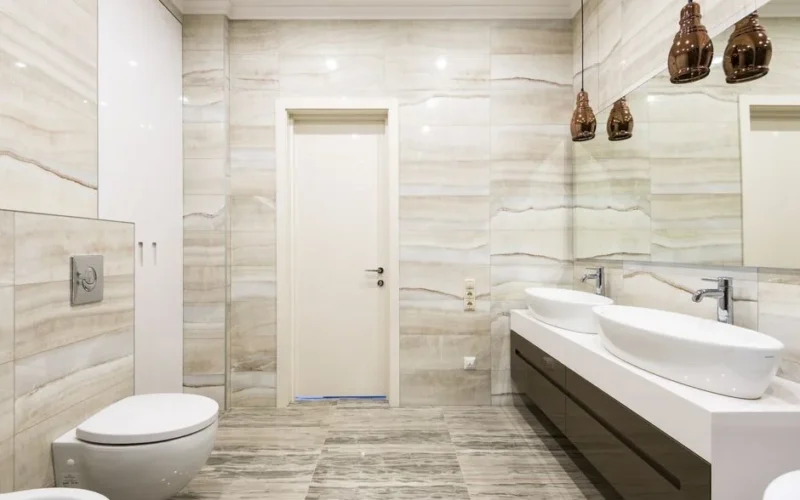 Luxurious bathroom featuring dual sinks, mirrors, and sleek design with beige tiles.