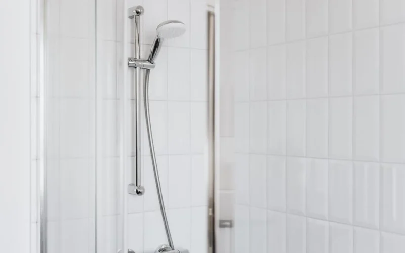 Stylish shower setup with chrome fixtures and clean white tiles.