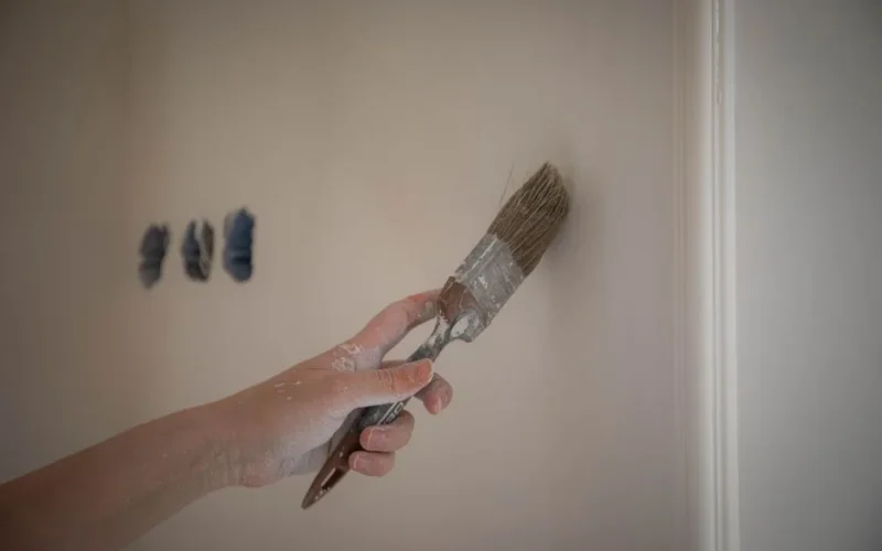 Close-up image of a hand painting a wall with a brush for home renovation.