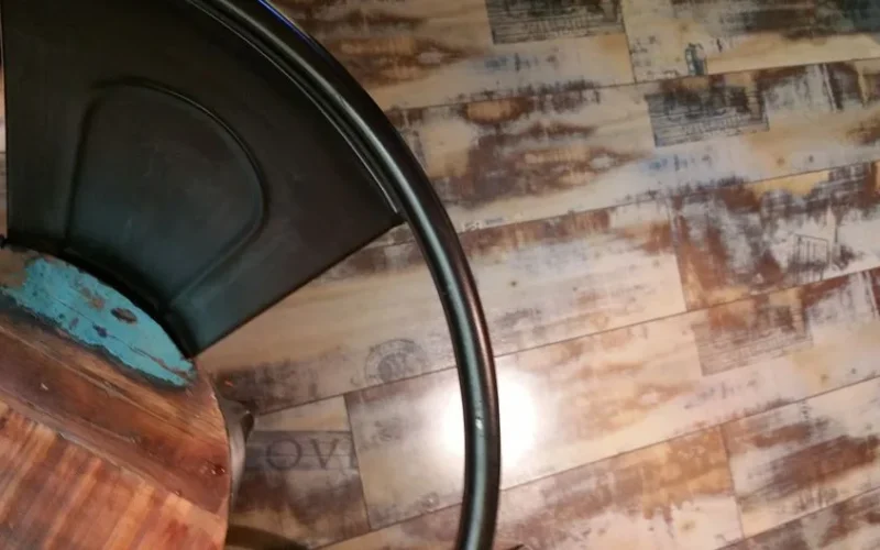 A rustic wooden table and industrial chair pair with wooden flooring.