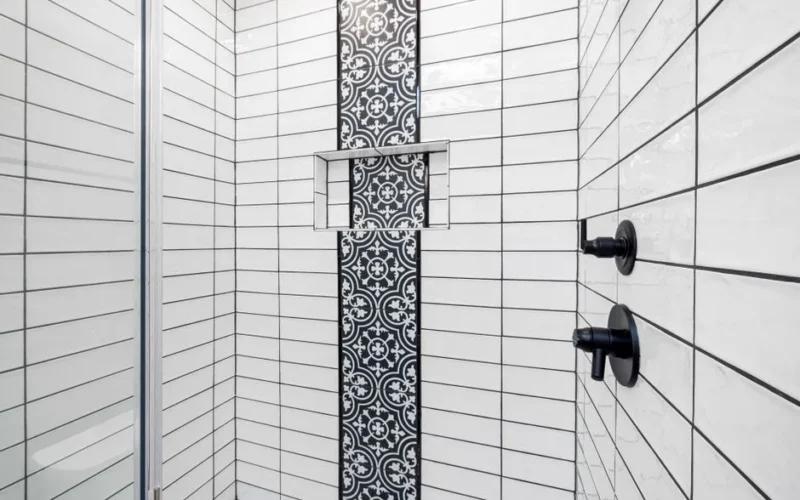 Stylish shower area featuring black and white geometric tiles and contemporary fixtures.