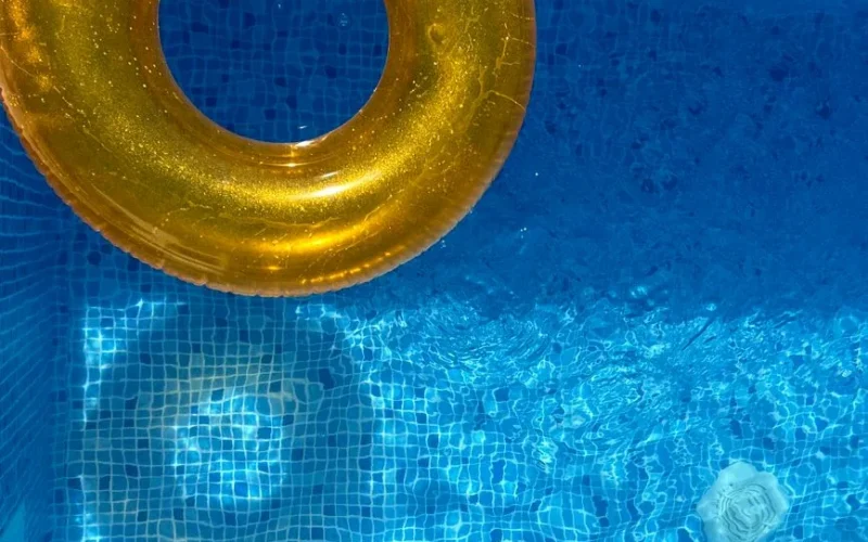Vibrant yellow inflatable ring floating in a sunlit blue swimming pool.