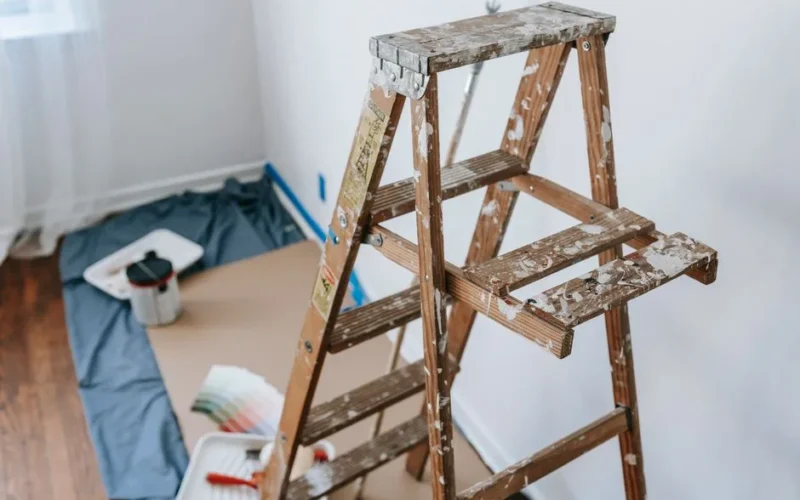 A messy stepladder and painting tools set up for a home interior renovation project.