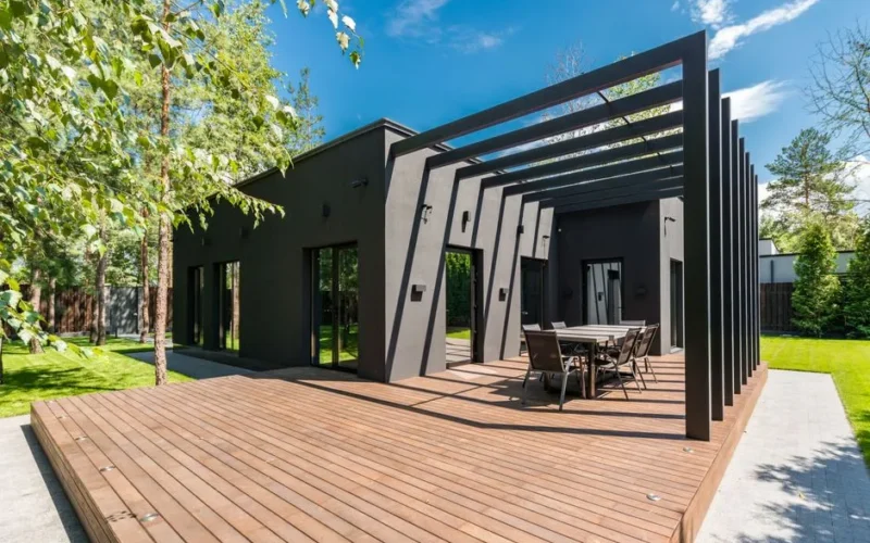 Stylish outdoor space with wooden deck and dining set, surrounded by lush greenery.