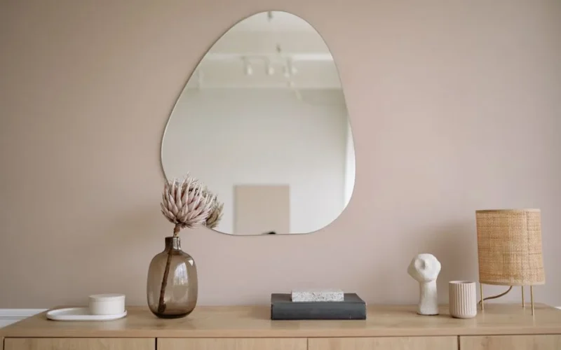 Stylish minimalist interior featuring a mirror, decorative vase, and lamp.